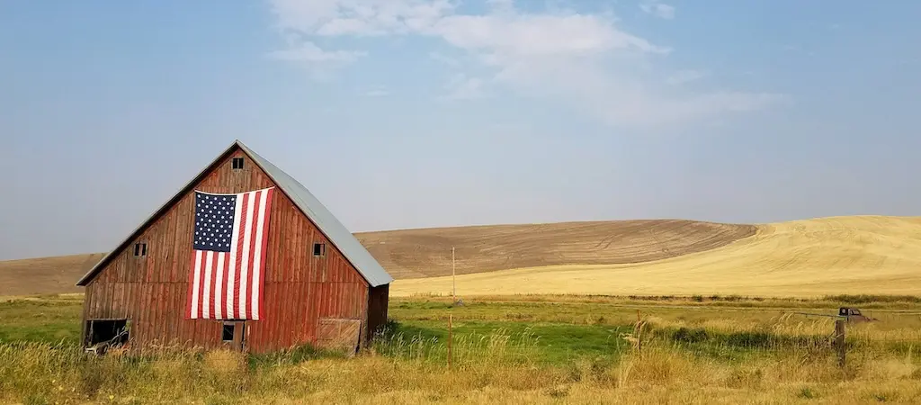 American flag displayed on a barn in a rural United States landscape